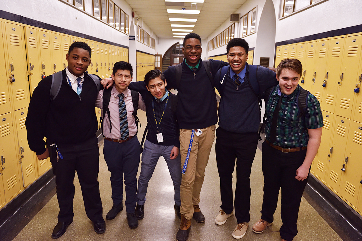 Group of smiling students gather in school hallway